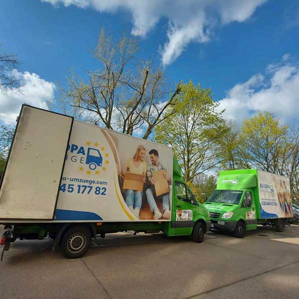 Fuhrpark von Europa Umzüge – mehrere grüne Umzugsfahrzeuge unter blauem Himmel